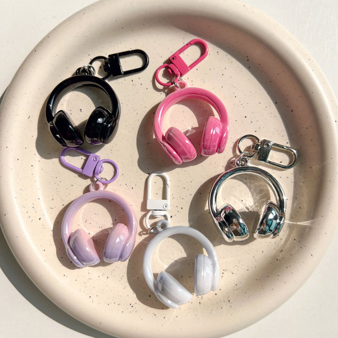 Colorful keychains shaped like headphones on a speckled ceramic plate.