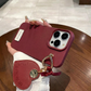 Red phone case with keychain held by a hand on a wooden surface