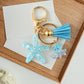 Keychain with blue tassel and starfish charm on a wooden surface